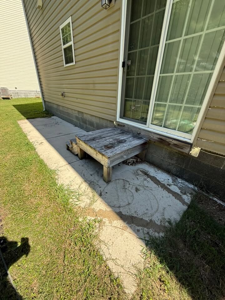 Concrete pad behind a house, stained and dirty before cleaning