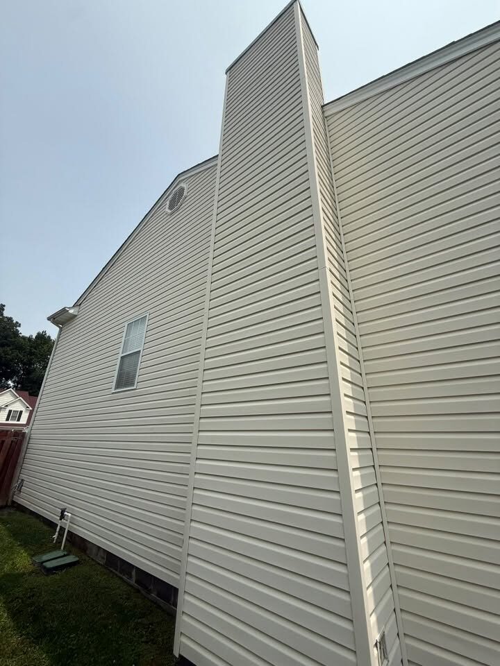 Tall stretch of cream vinyl siding and a chimney chase, freshly washed