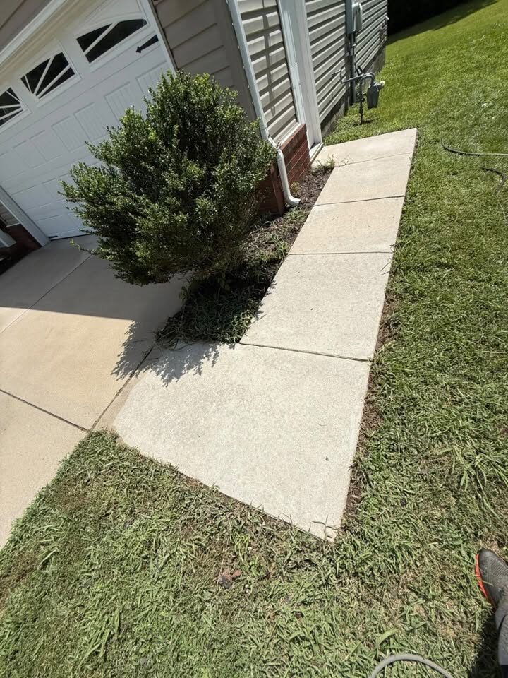 Narrow concrete walkway beside a garage, cleaned to a bright even tone
